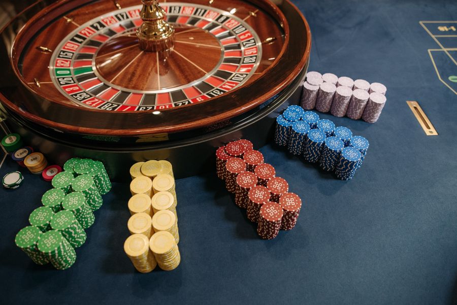 Roda roulette dan tumpukan chip warna-warni di meja kasino