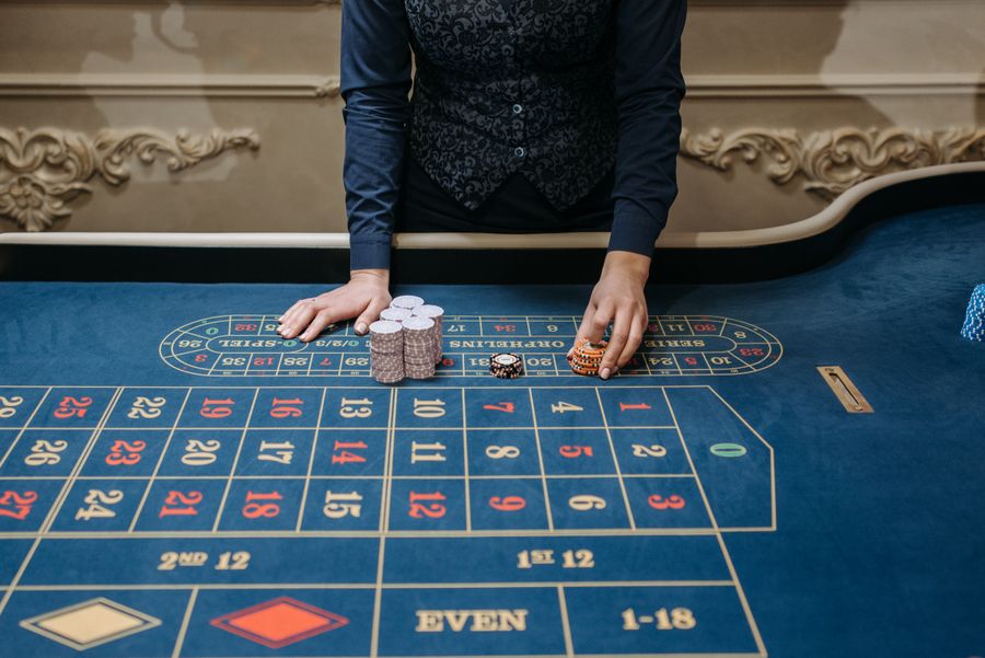 Dealer kasino menyusun chip kuning di atas meja roulette